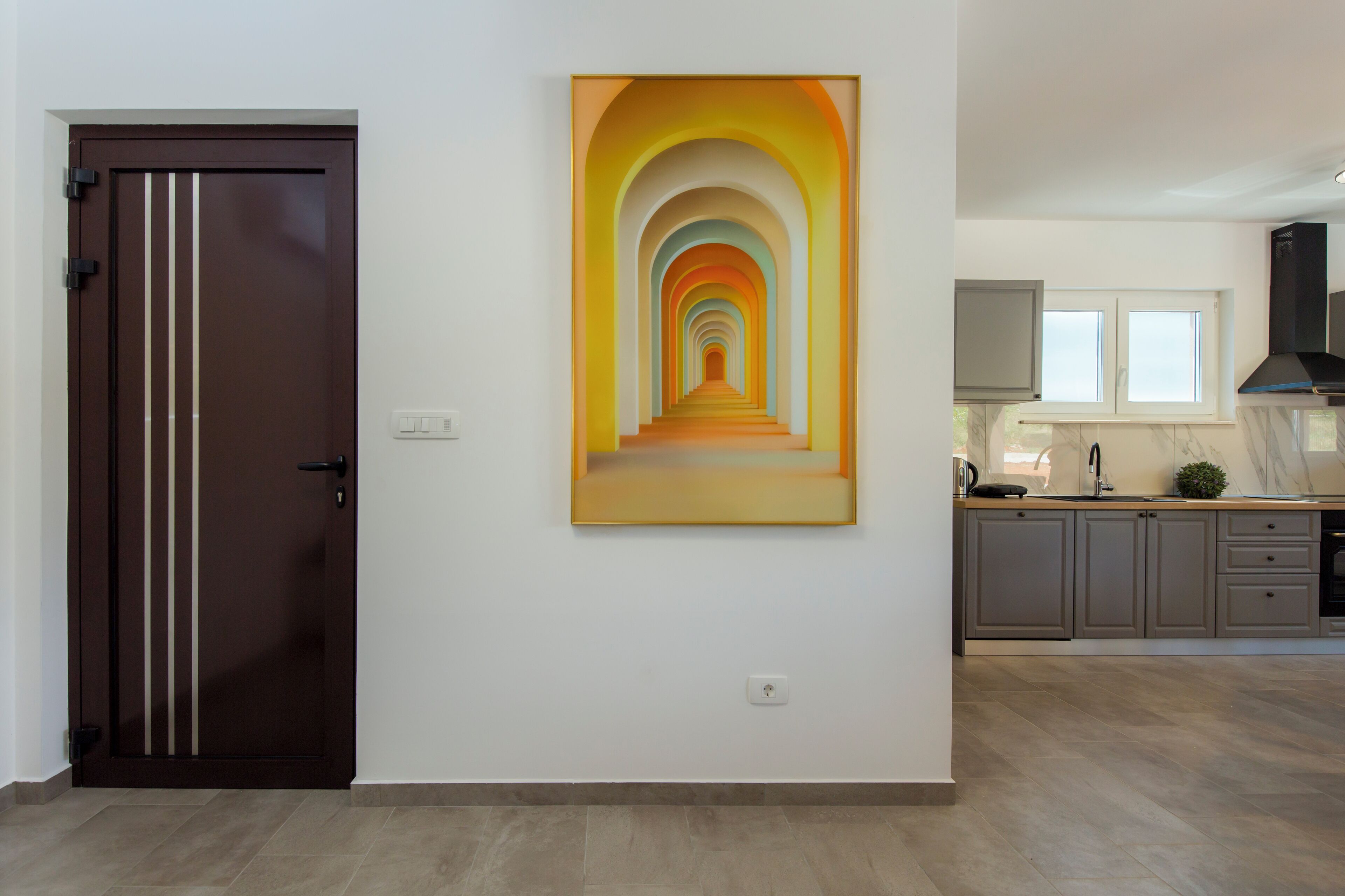 Eine moderne Küche mit grauen Schränken, einer schwarzen Dunstabzugshaube und einem Fenster über der Spüle.