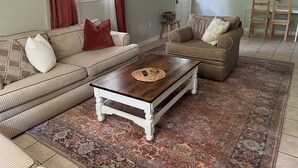 Ein Wohnzimmer mit gestreiften Sofas, einem Holztisch und einem gemusterten Teppich.