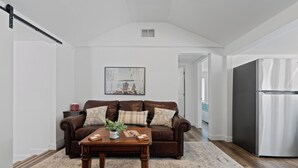 A living room with a brown leather sofa, a wooden coffee table, and a painting on the wall.