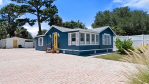 A small, single-story building with a blue exterior and white trim, featuring a front door and windows.