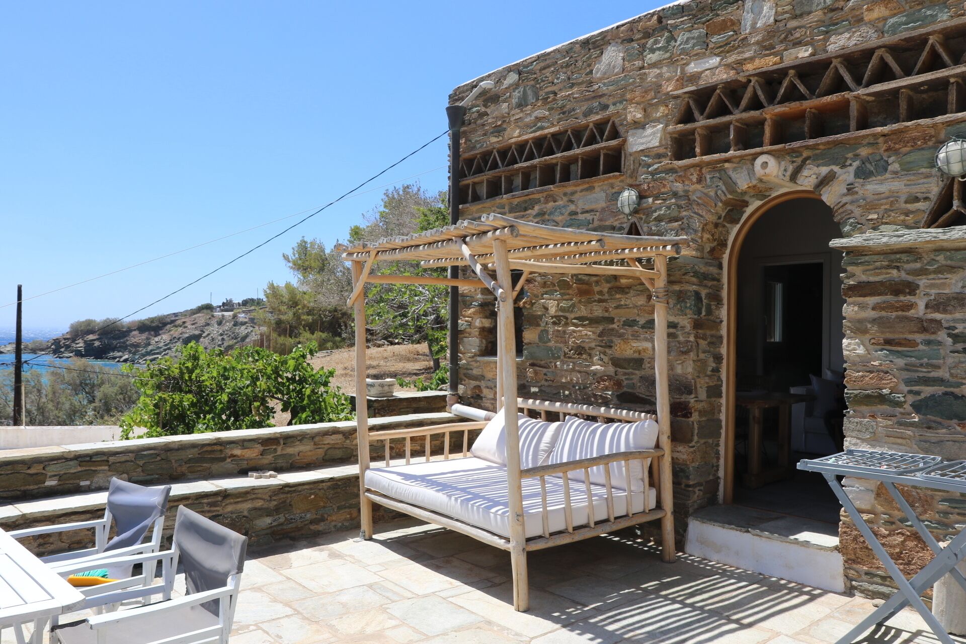 A stone building with a wooden four-poster bed and a table with chairs.