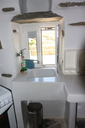 Une cuisine de taille réduite, équipée d’un évier, d’une cuisinière et d’une fenêtre.