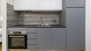 A modern kitchen with grey cabinets, a built-in oven, and a stainless steel sink. - Casa da Suite Cadorna (Milan)