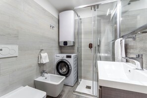 A modern bathroom with a glass shower, a washing machine, a bidet, and a sink. - Casa da Suite Cadorna (Milan)