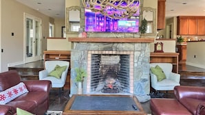 A living room with a stone fireplace, leather sofas, and a television mounted above the fireplace. - Bearities - 2 homes, sleeps 28, hot tubs, grills! (Killington)