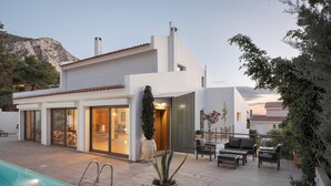 Ein modernes Haus mit Swimmingpool, Sitzgelegenheiten im Freien und Bergblick.