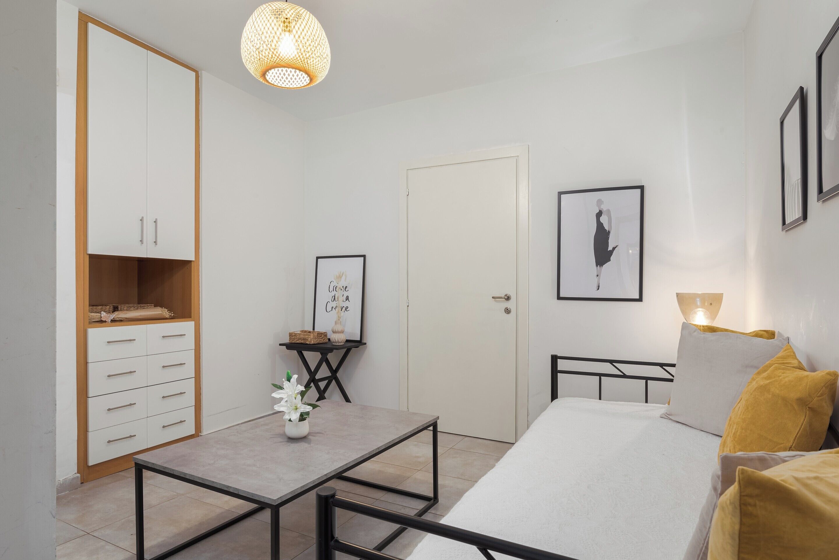 A bedroom with a bed, bedside table, wardrobe, and a framed picture on the wall.