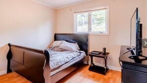 Ein Schlafzimmer mit einem Bett, einem kleinen Tisch, einem Fernseher und einem Fenster.