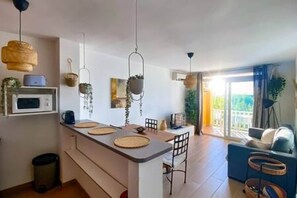 A modern kitchen with a central island, hanging plants, and a dining area with chairs.