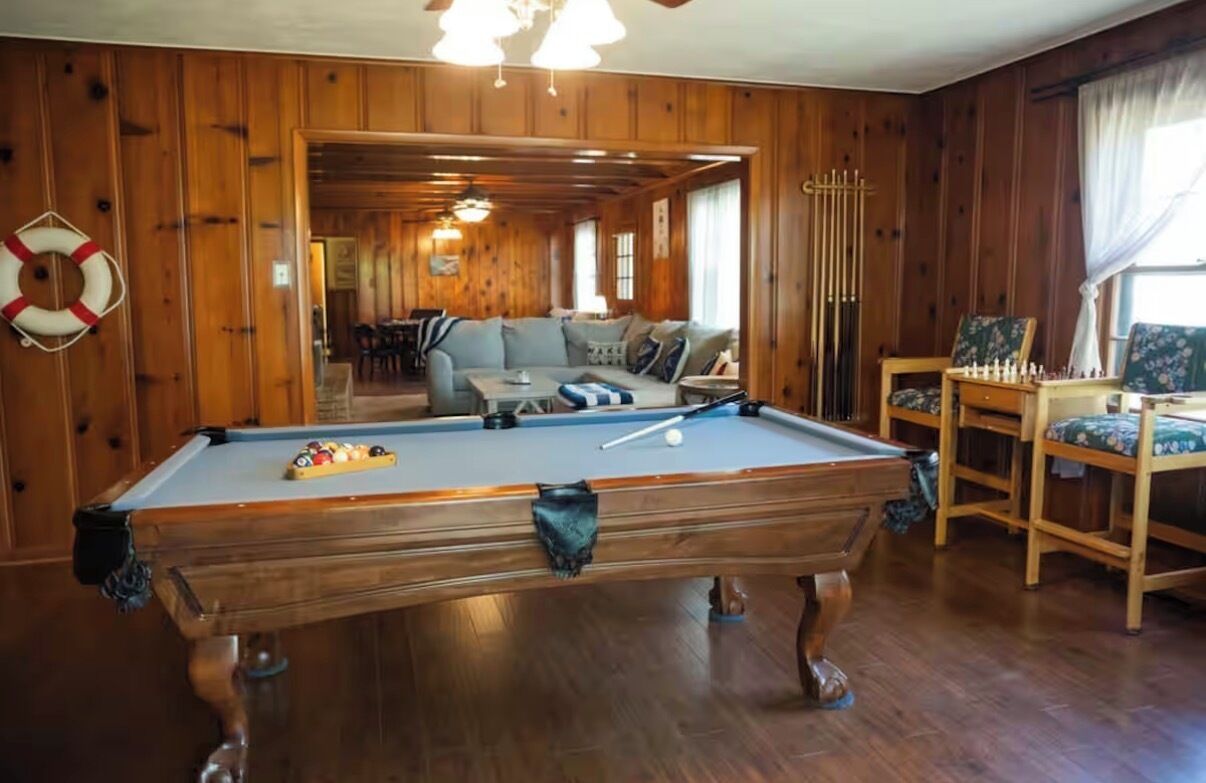 Ein Billardtisch in einem Raum mit Holzwänden und einer Couch.
