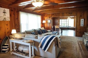 Ein gemütliches Blockhaus-Interieur mit einer Couch, einer Lampe und einem Billardtisch.