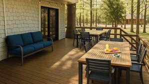 An outdoor patio with a wooden deck, a blue sofa, and a wooden table with chairs. - Cozy lake retreat in Sand Point! Game room with deck and views of Lake Texoma. (Mead)