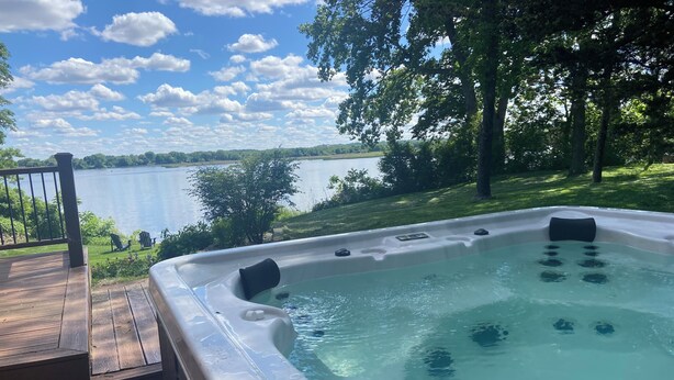 Un jacuzzi con terraza de madera y vista a un lago.