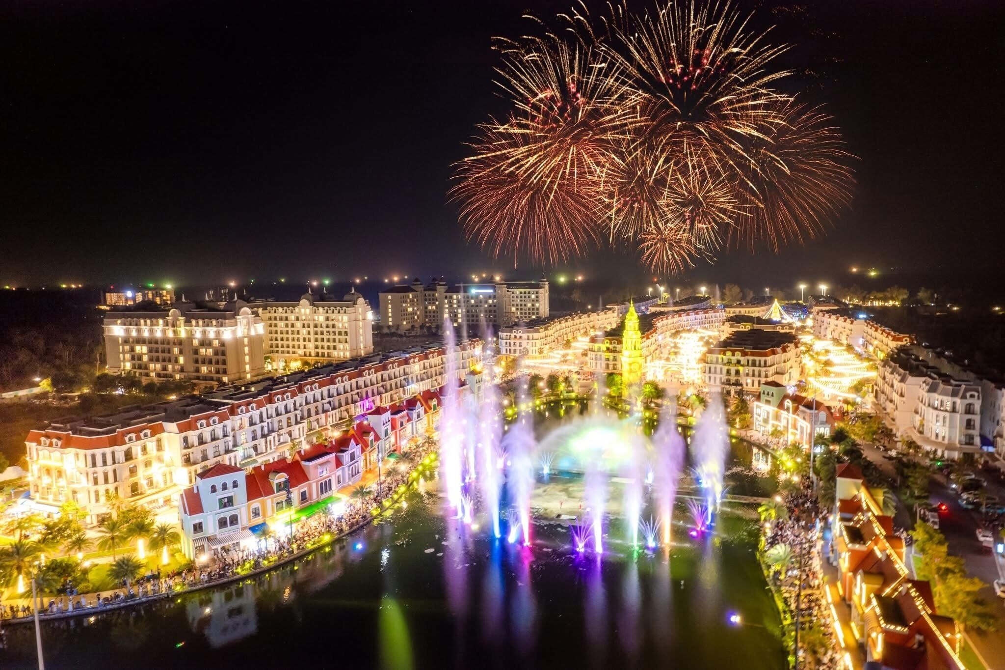 Un hotel con vista al agua, un espectáculo de fuentes y fuegos artificiales de fondo.