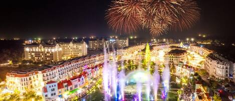 Un hotel con vista al agua, un espectáculo de fuentes y fuegos artificiales de fondo.