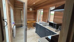 Una cocina moderna con paneles de madera, una isla grande y vistas a través de un ventanal abierto.