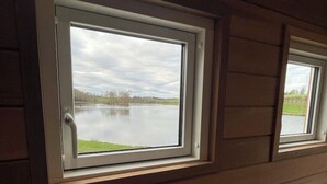 Una habitación con vistas a un lago a través de una ventana de marco blanco.