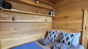 A cozy bedroom with a wooden ceiling, a bed with a blue quilt, and shelves with various items. - Cedar Lodge - Idyllically situated Lakeside & private hot tub fishing riding (Northumberland)