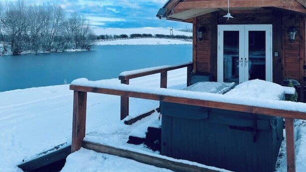 A wooden cabin with a porch and a view of a lake. - Cedar Lodge - Idyllically situated Lakeside & private hot tub fishing riding (Northumberland)