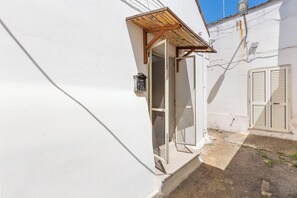 Un bâtiment blanc avec une porte en bois et une petite fenêtre.