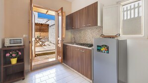 Una cocina compacta con armarios de madera, microondas integrado y un refrigerador.