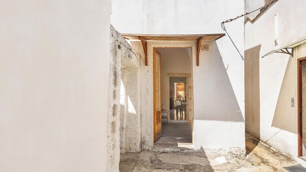Un callejón estrecho con una puerta de madera y una pequeña mesa al fondo.