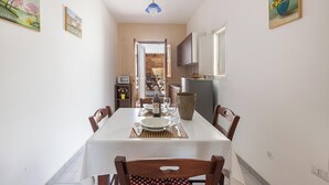 Un comedor con una mesa dispuesta para cuatro, sillas, una botella y un florero sobre la mesa.