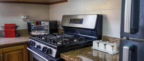 Une cuisine équipée d’une cuisinière à gaz, d’un four, d’un four à micro-ondes et d’un grille-pain rouge.