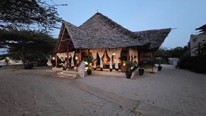 A thatched-roof building with a covered outdoor seating area and potted plants.