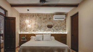 Ein Schlafzimmer mit einer Steinwand, einem Bett mit Holz-Kopfteil, einer Klimaanlage und einem Schachbrettmuster-Boden.