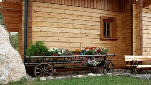 Eine Holzjagdhaushütte mit einem Holzwagen, beladen mit Blumen, und einer Bank.