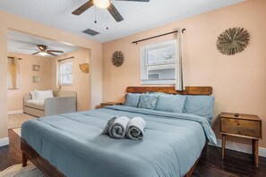 A bedroom with a bed, a nightstand, a ceiling fan, a window with blinds, and a wall decoration. - Tropical Spa Escape! Pool/Spa/Sauna WIFI 4Bdrm 8 Min Bch (Boynton Beach)