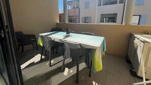 Un balcon avec une table et des chaises, une plante en pot et un lave-linge.