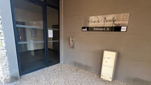 Une entrée avec une porte vitrée, une enseigne indiquant « Bâtiment A » et un clavier de sécurité fixé au mur.