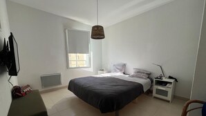 Une chambre à coucher comprenant un lit, une table de chevet, une chaise et un luminaire suspendu.