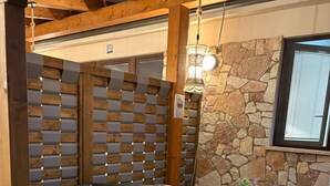 A hot tub in a covered outdoor area with a stone wall and wooden beams.