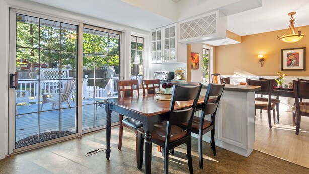A spacious dining area with a large table and chairs, a kitchen area with a countertop, and a view of the outdoors through large sliding glass doors. - Spacious 5-Bedroom House in Rockville Fast WiFi, Gaming Area & Fenced Yard (Rockville)