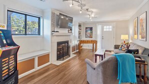 A living room with a fireplace, a foosball table, a television, and a sofa. - Spacious 5-Bedroom House in Rockville Fast WiFi, Gaming Area & Fenced Yard (Rockville)