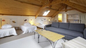 Ein gemütliches Zimmer mit zwei Einzelbetten, einem Schlafsofa, einem kleinen Tisch und einem Deckenventilator.