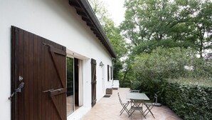 Eine Terrasse mit Tisch und Stühlen, eine Holztür und eine weiße Wand.