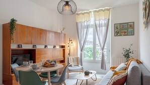 Un salon moderne comprenant un canapé, une table à manger avec des chaises, un téléviseur et un coin cuisine avec des placards.