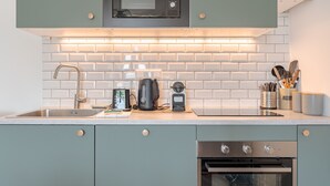 Une cuisine moderne dotée d’un four à micro-ondes encastré, d’appareils électroménagers en acier inoxydable et d’un dosseret carrelé.