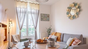 Un salon chaleureux avec une table à manger ronde, un canapé gris et un élément décoratif mural.