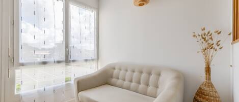 A room with a white sofa, a wicker vase, and a wicker side table.