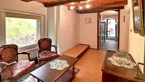 A room with a wooden bench, two ornate chairs, a small table with a glass cover, and a large mirror on the wall. - Vert Olive - Maison proche Sélestat, Colmar (Rombach-le-Franc)