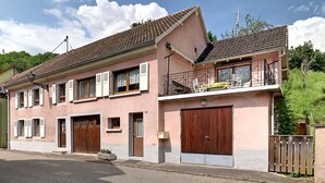 A two-story house with a balcony, a garage, and a driveway. - Vert Olive - Maison proche Sélestat, Colmar (Rombach-le-Franc)