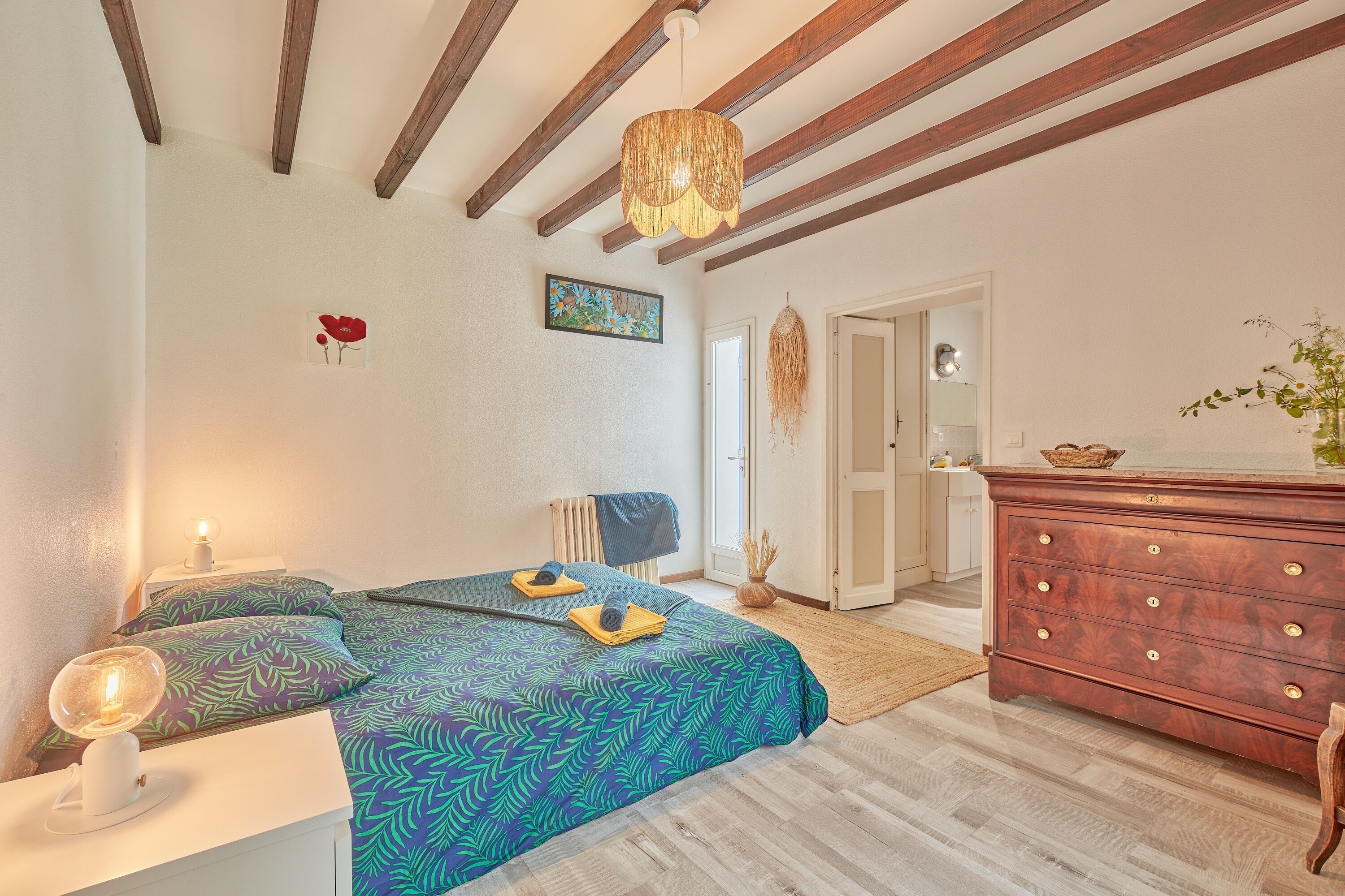 Un dormitorio con cama, mesitas de noche, cómoda y lámpara colgante.