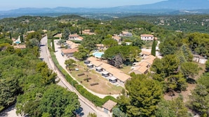 Vue aérienne d’un quartier résidentiel avec des maisons, une route et la végétation environnante.
