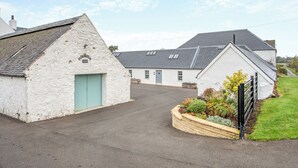 A white farmhouse with a blue door and a small garden in front. - 2 bedroom accommodation in Ayr (Ayr)