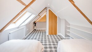 A bedroom with a sloped ceiling, wooden beams, a checkered floor, and a white radiator. - 2 bedroom accommodation in Ayr (Ayr)